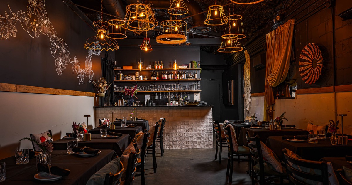 Interior, tables and chairs in dining area with bar in the back