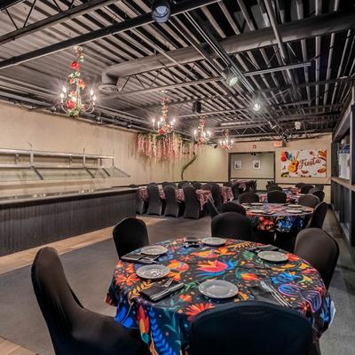 Interior, tables with colorful tablecloths, decorative lighting, and wall art.