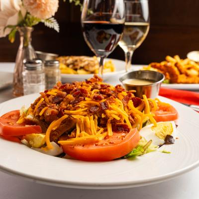 Crispy chicken salad with glasses of wine in the background