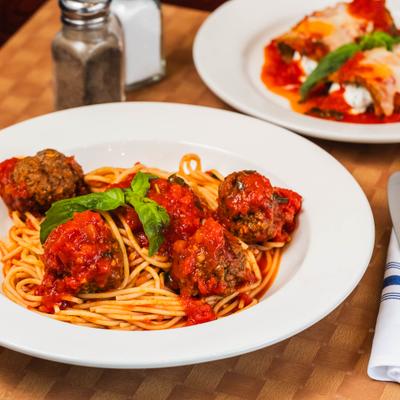 Spaghetti with meatballs topped with tomato sauce and basil leaves.