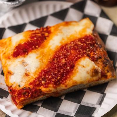 Slice of Sicilian style pizza topped with tomato sauce and mozzarella.
