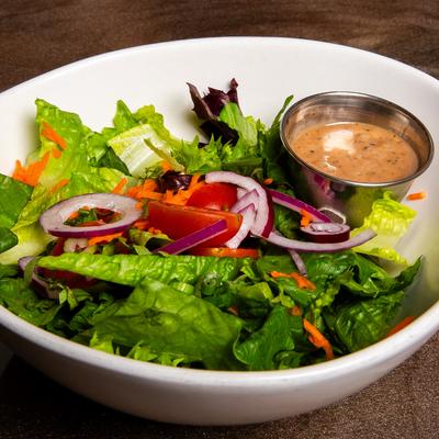 Mixed greens salad with a side of dressing.