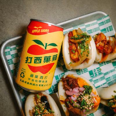 Canned drink beside stuffed buns on a tray.