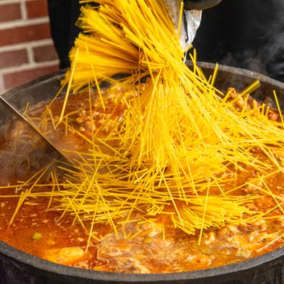 Dry pasta added to a large simmering pot.