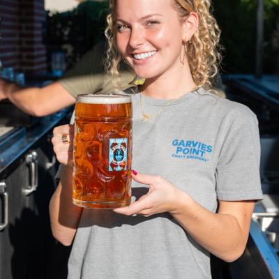 Smiling person holding a large glass of beer.