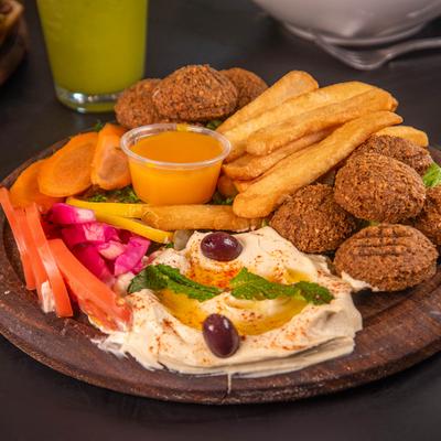 Falafel served with hummus, pickled veggies, amba, and fries.