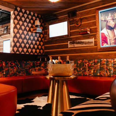 Lounge with red floral sofas, a gold table with champagne, and eclectic decor.