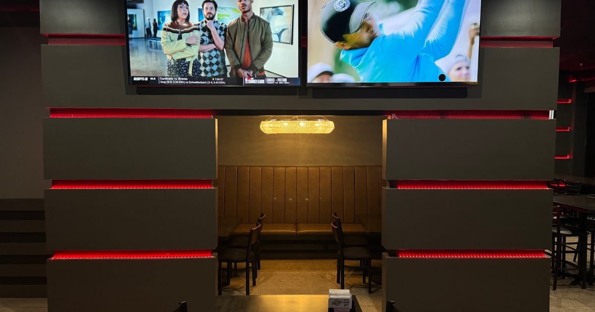 Interior with a banquette bench, tables, chairs,  andTVs