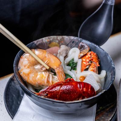 Seafood udon soup featuring a whole crayfish, a large prawn, and thick noodles.