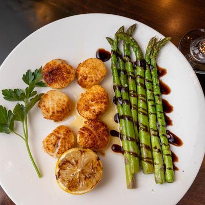 Scallops, served with grilled asparagus, top view, closeup.