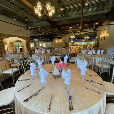 A room with round tables and chairs set and decorated for banquet