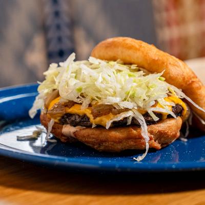 Cheeseburger on a frybread bun topped with lettuce.