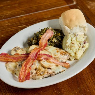 Smothered chicken breast topped with bacon, served with mashed potato and colard greens.
