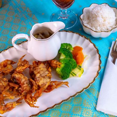 Deep-fried soft-shell crab served with steamed rice, broccoli, carrots, and a side of sauce.