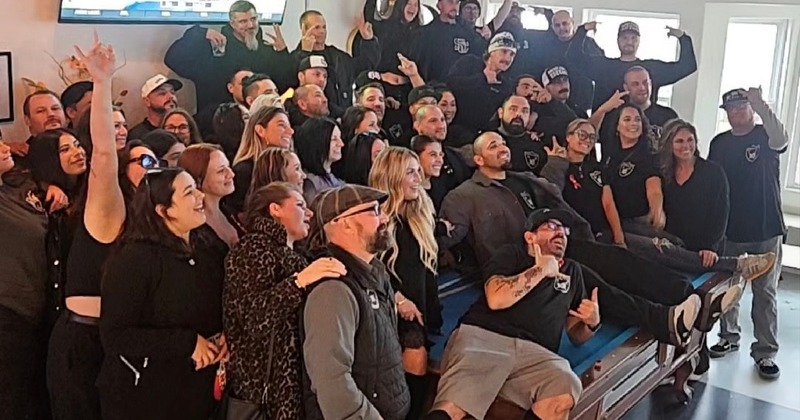 A large group photo where everyone is wearing the same black shirt memorializing a loved one
