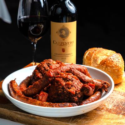 Plate of sausage and meatballs served alongside bread and red wine.