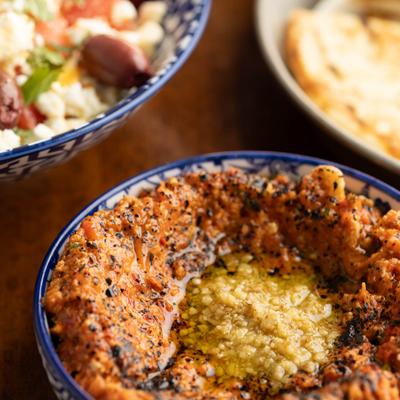 Muhammara dip garnished with black sesame seeds and olive oil.