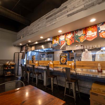 Interior with counter seating, wooden accents, rustic-style walls and decorative hanging banners.