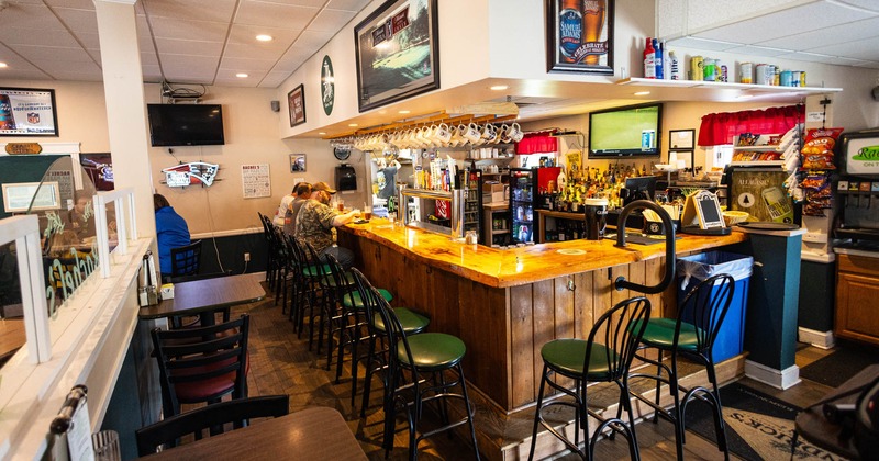 Bar interior with a wooden counter and green bar stools