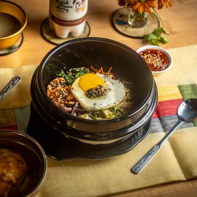 Rice topped with bulgogi, veggies and fried egg, served in a bowl.