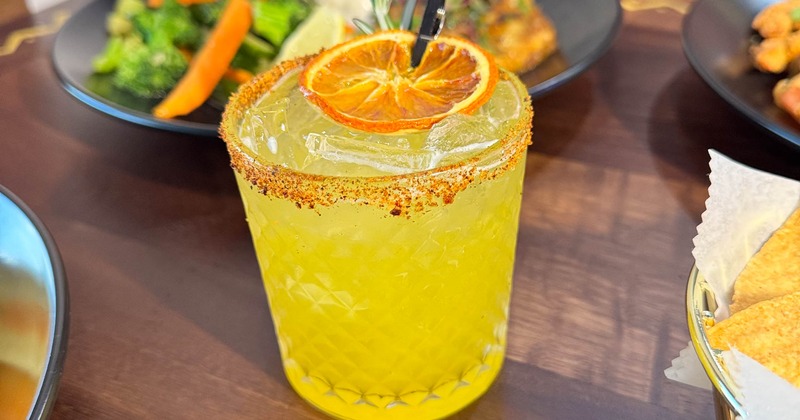 Cocktail in a rocks glass served on the table with variety of dishes