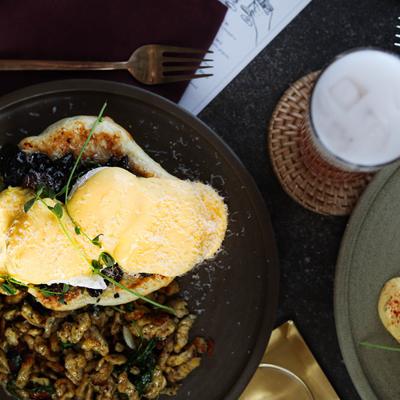 A plate with two poached eggs on a bun topped with hollandaise sauce and sprinkled cheese.