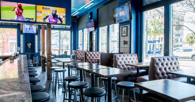 Interior, bar, lined up tables and chairs, booths, large TV screeens