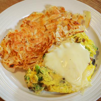 Broccoli and mushroom omelet, topped with cheese, served with hash browns
