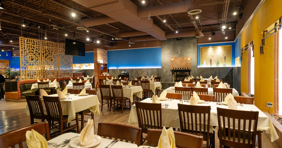 Restaurant interior with neatly arranged tables, wooden chairs, vibrant walls, and ambient lighting