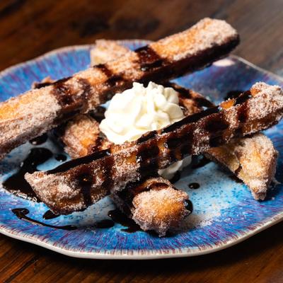 Churros, with chocolate drizzle, and whipped cream.
