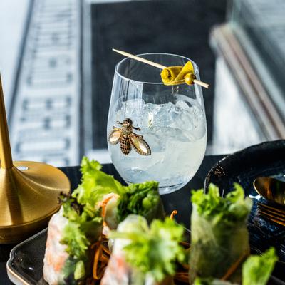 Electric Kiss cocktail beside fresh spring rolls.