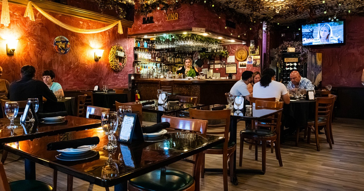 Restaurant interior featuring set tables and a well-stocked bar in the background
