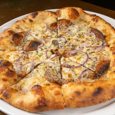 Pizza with Yukon potato slices, black pepper, onion, garlic sauce, and cheese.