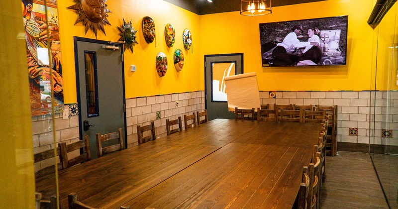 Interior, adjoined tables, yellow walls with a TV and decorative fiesta masks