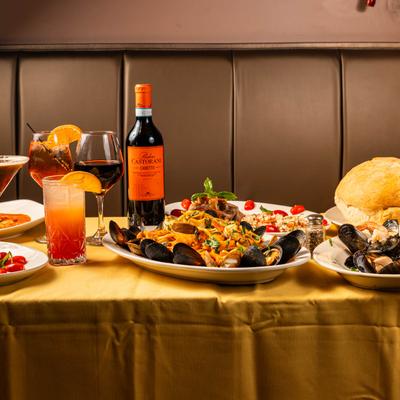 A table with assorted dishes, cocktails, and wine.