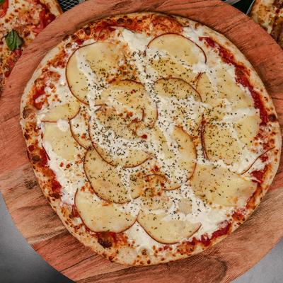 Pizza topped with cheese, potatoes and dried herbs, overhead view.