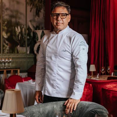 Chef smiling on the floor with dining room decor in the background.