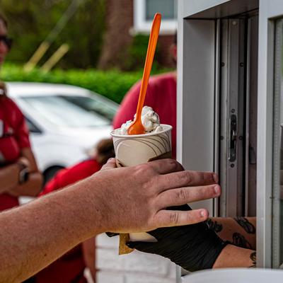Customer receiving an ice cream in a cup from an employee.