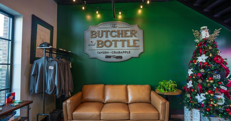 Interior with green wall, leather couch, decorative sign, clothing rack and Christmas tree