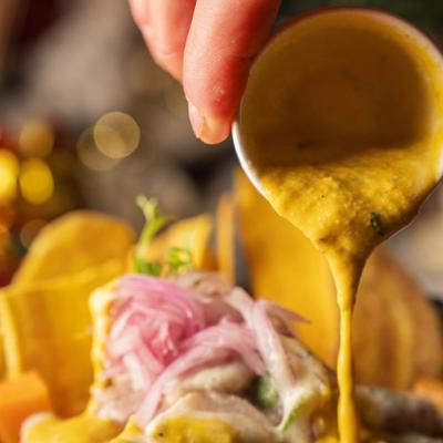Ceviche dish being topped with sauce, closeup.