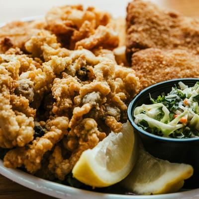 Fried seafood platter with clams, fish, cloleslaw and lemon wedges, close-up.