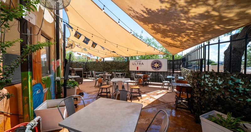 Outdoor dining area with tan canopies, metal tables