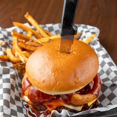 Burger topped with barbecue sauce, onion rings and cheese, served with fries.