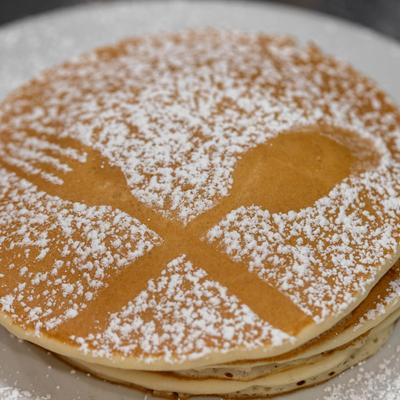 Pancakes with crossed fork and spoon sugar stencil.