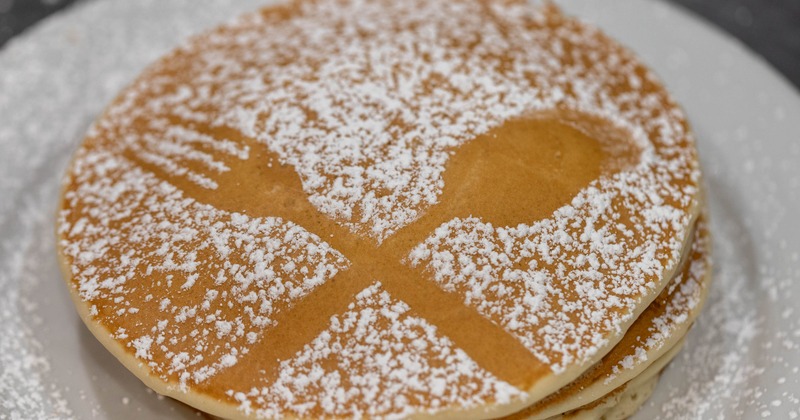 Pancakes dusted with powdered sugar on a white plate