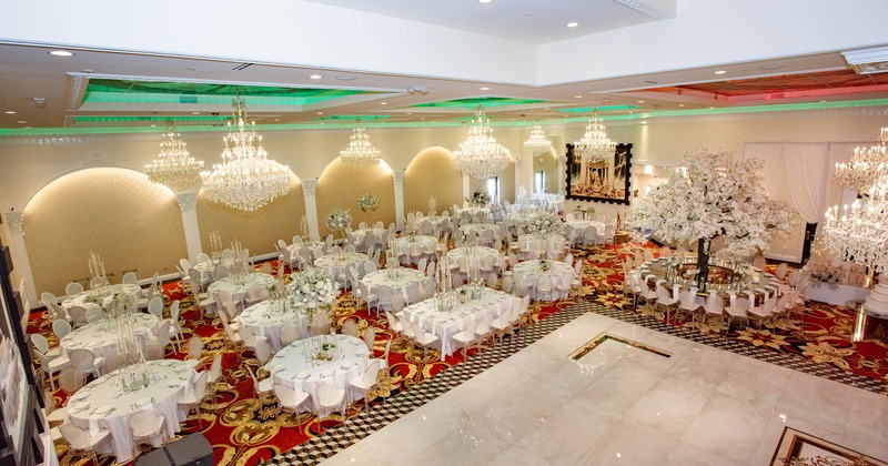 Decorated banquet hall - chandeliers, white tables, floral arrangements and red - gold carpet