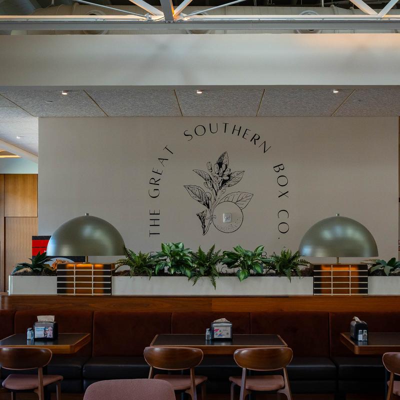 Modern dining area with booths, plants, pendant lights, and a decorative wall