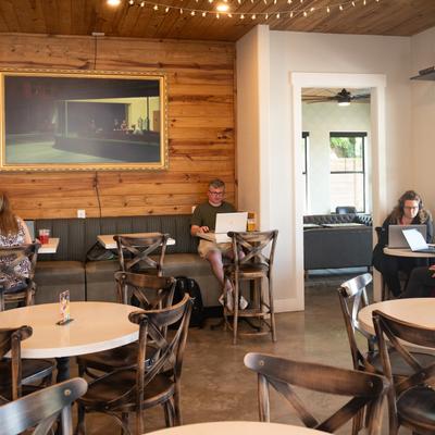 People work on laptops in a room with wood-paneled walls and a painting reproduction on a wall.