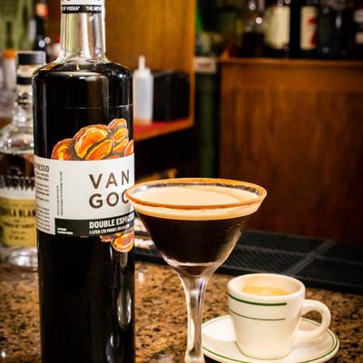 Double espresso vodka bottle with Espresso Martini cocktail on bar counter.
