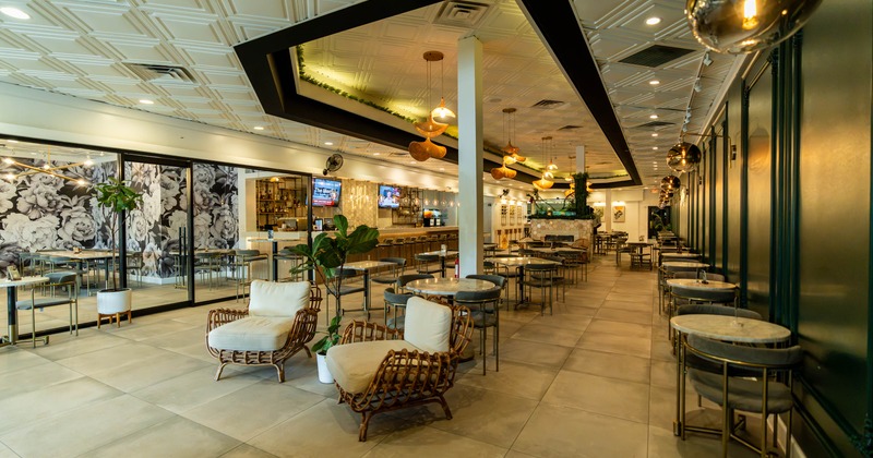 Interior, open space seating area, round tables for two and four, wicker armchairs
